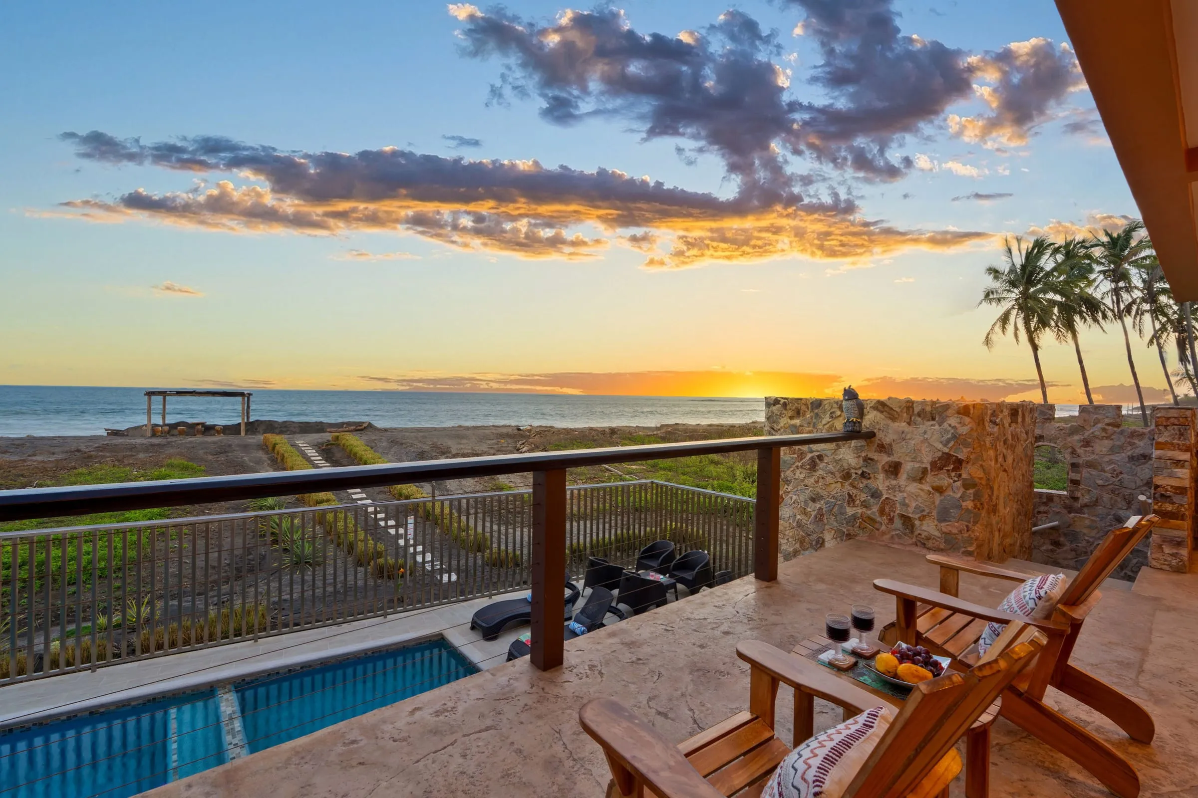 Balcón con sillas Adirondack sobre la piscina, frente al atardecer en el Pacífico