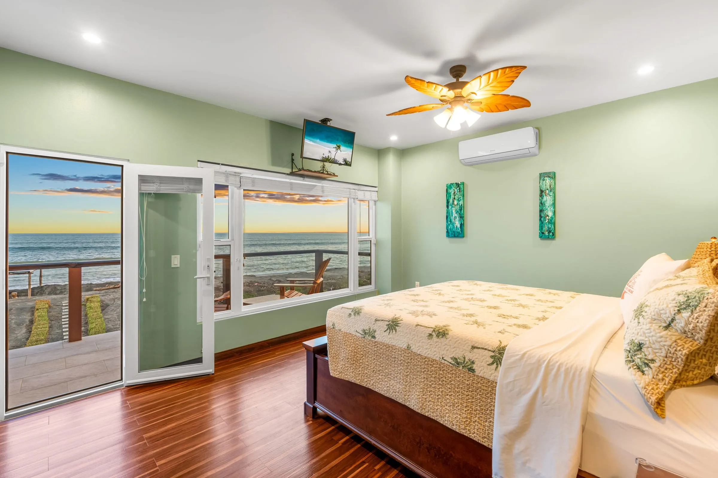 Habitación con cama king y puertas de vidrio hacia el mar al atardecer