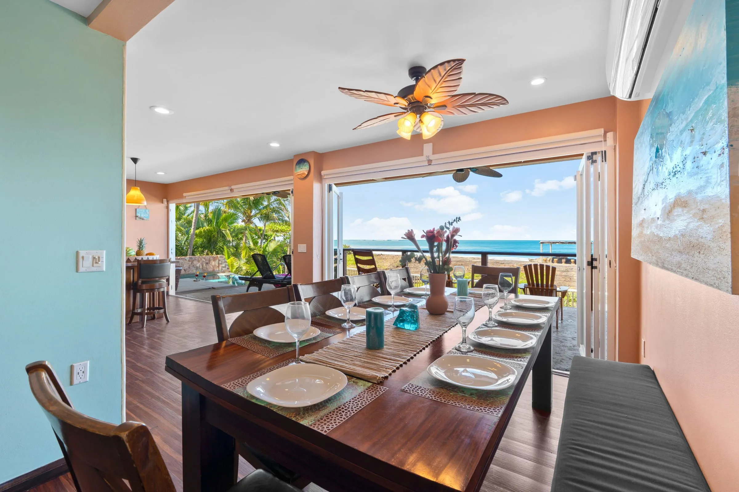 Mesa de comedor para diez junto a las puertas abiertas a la terraza con vista al mar