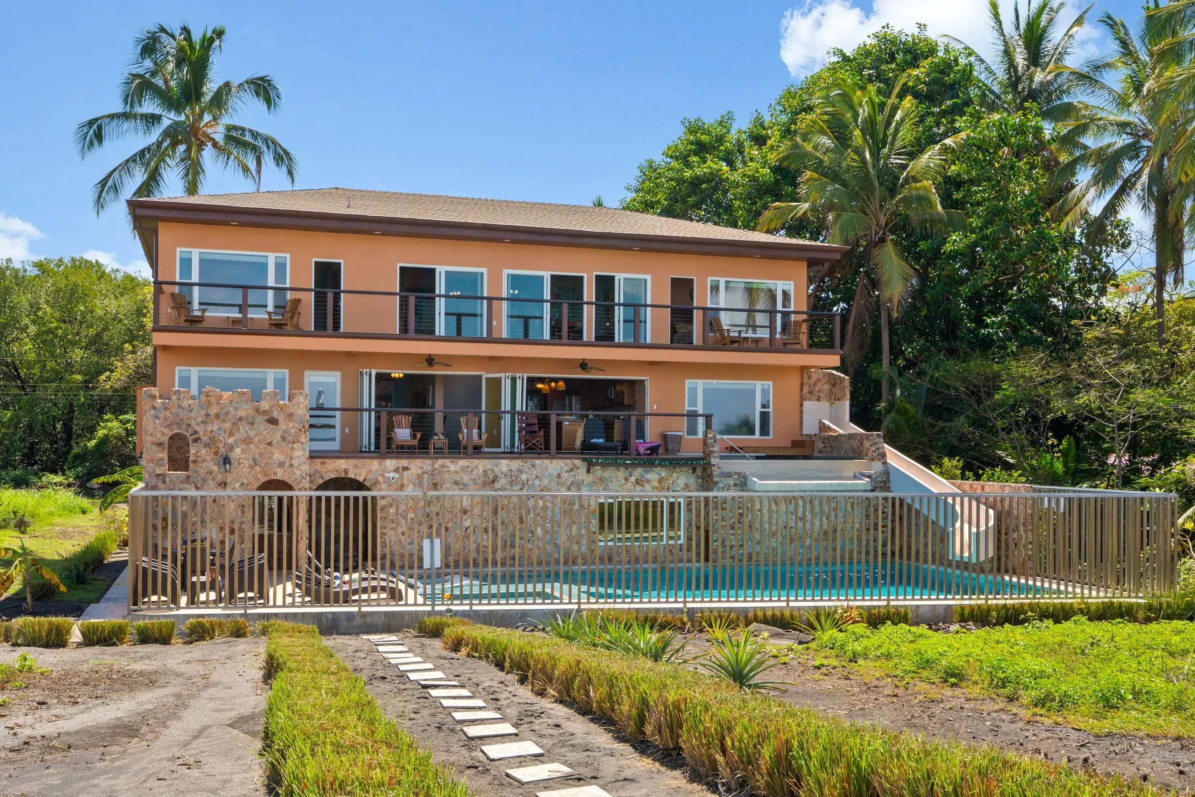 La casa y el sendero del jardín vistos desde la playa, de día