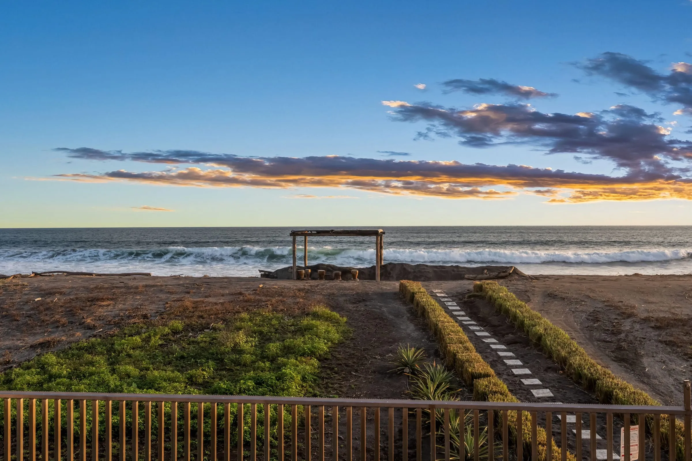 Sendero del jardín hacia Playa Junquillal y un rancho de playa, con el mar al fondo