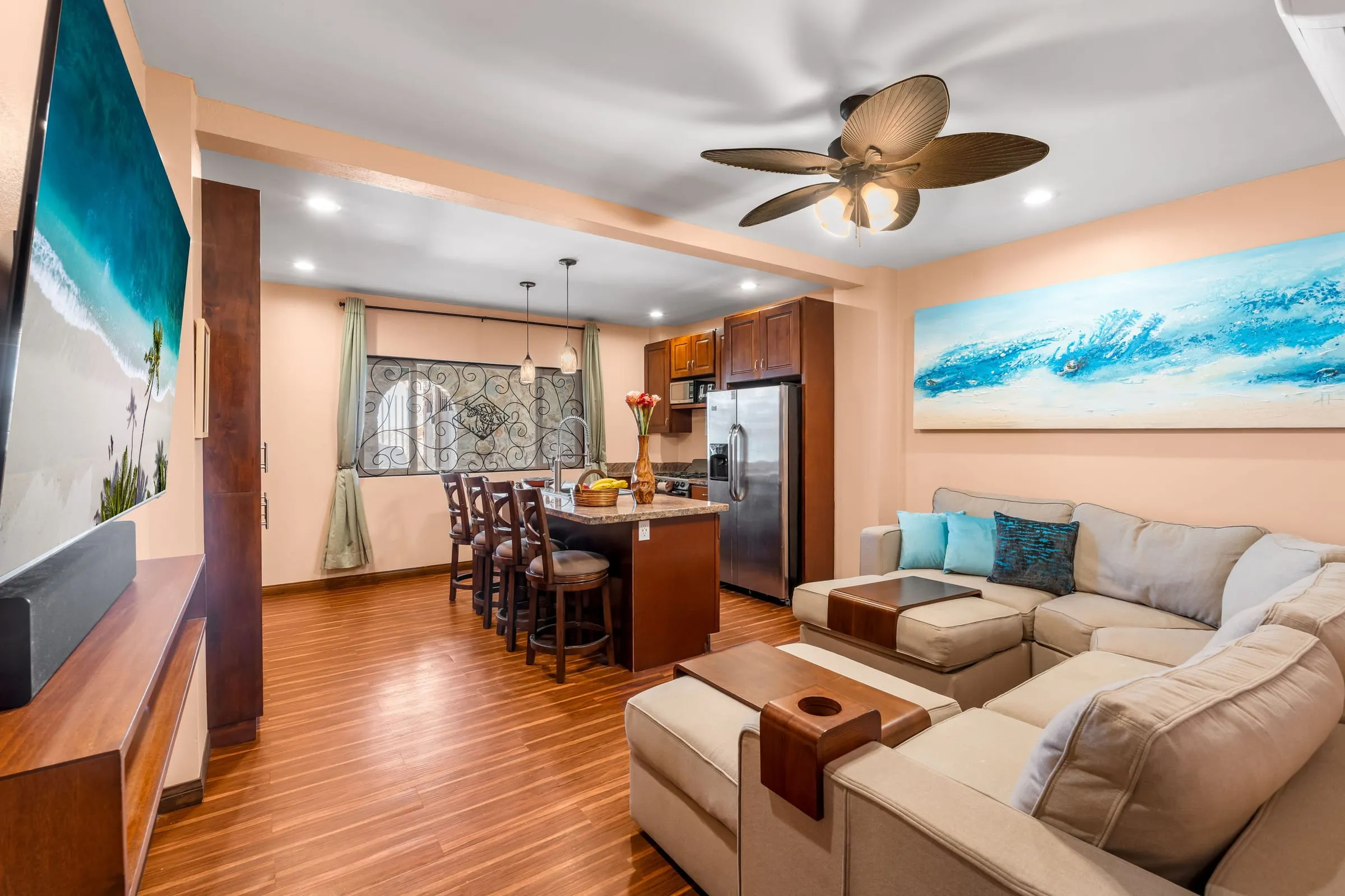 Sala con sofá seccional y cuadros del mar, con una cocina al fondo