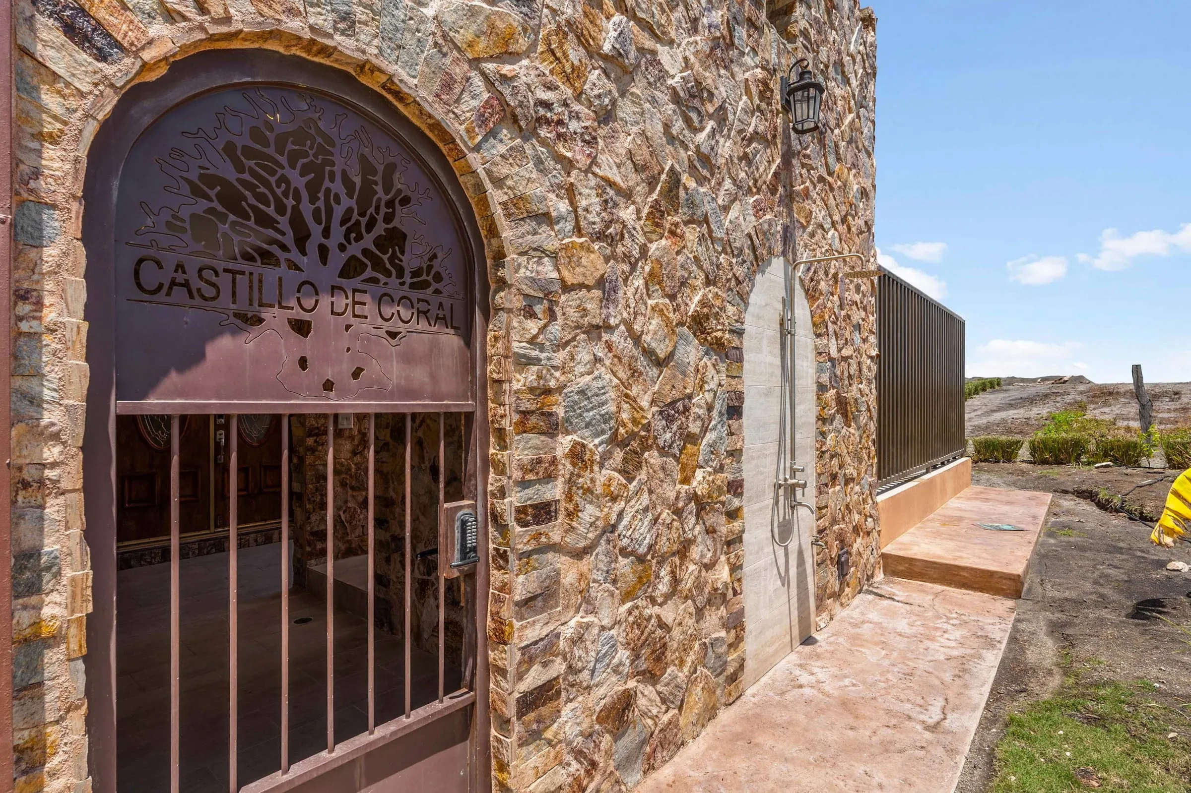Entrada de piedra con un portón de hierro con el nombre Castillo de Coral