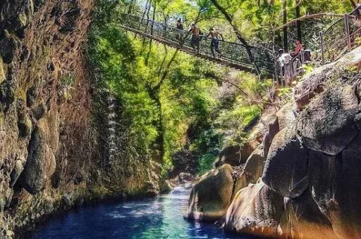 Un cañón de río con puente colgante y una catarata