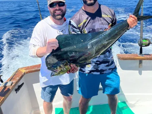 Dos pescadores en un bote sosteniendo un dorado grande