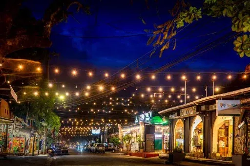 Una calle de Tamarindo de noche con luces y tiendas